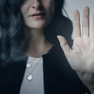 Image d'une femme tendant la main avec un geste de stop, symbolisant la lutte contre le harcèlement moral - Axia Consultants