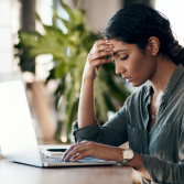 Femme déprimée devant son ordinateur, illustrant l'impact du stress de la rentrée sur la qualité de vie au travail (QVCT) et les risques psychosociaux.
